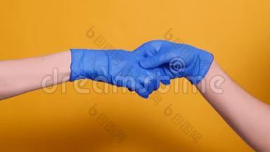 两人戴着黄色背景的蓝色医用手套握手